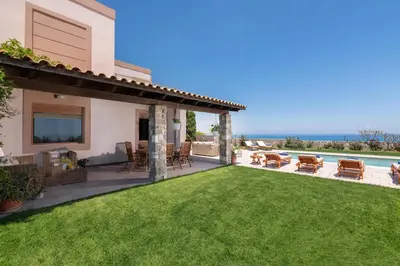 a backyard with a lawn and a view of the ocean at Majestic View Villa in Kolimbia