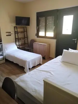 a hotel room with two beds and a tv at Serafi Cozy Rooms in Archangelos