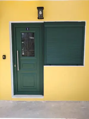 a green garage door on a yellow building with at Serafi Cozy Rooms in Archangelos