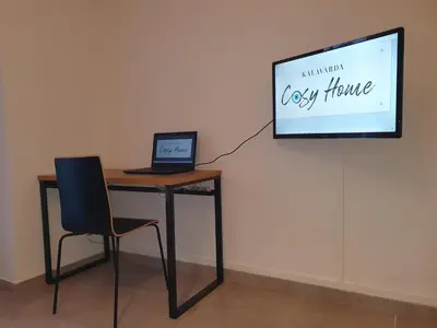 a desk with a laptop and a chair in front of a screen at Kalavarda Cosy Home 2 in Kalavárda