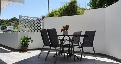 a table and chairs on a balcony with a white wall at Kalavarda Cosy Home 2 in Kalavárda