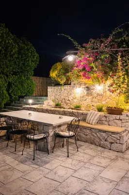 a table and chairs and a stone wall with flowers at Wine & Vineyard Retreat Emarmene in Koskinou