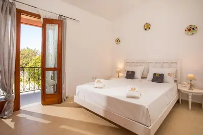 a white bedroom with a bed and a balcony at Wine & Vineyard Retreat Emarmene in Koskinou