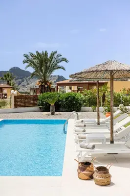 a pool with white lounge chairs and an umbrella at Villa Santa Maria with private pool and sea view in Afantou