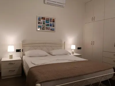 a bedroom with a bed with two night stands and two lamps at SUNNY HOLIDAYS APARTMENT in Kremasti