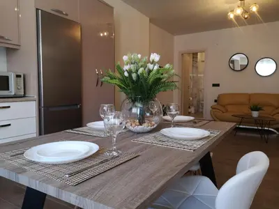 a table with plates and glasses and a vase of flowers at SUNNY HOLIDAYS APARTMENT in Kremasti
