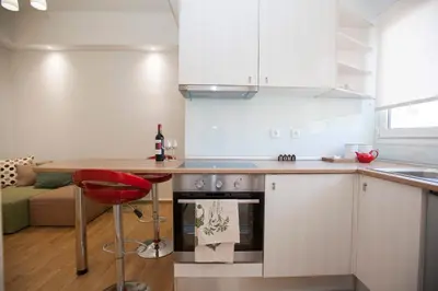 a kitchen with white cabinets and a red stool at Aegean Living in Rhodes Town