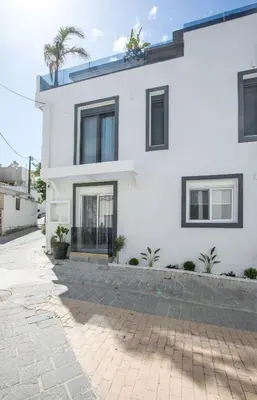 a white house with black windows and a courtyard at Casa Antonis - Modern Home with Jacuzzi near Faliraki in Kalithies
