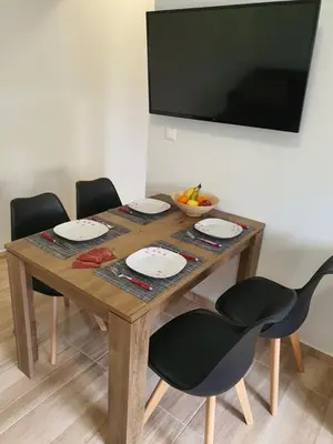 a wooden table with four chairs and a bowl of fruit at Perama View Apartments in Eleoúsa