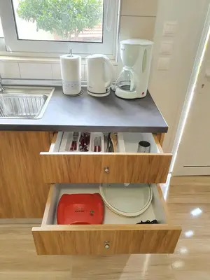 a kitchen with wooden drawers with cups and plates at Perama View Apartments in Eleoúsa