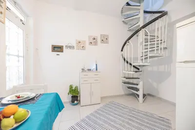 a white room with a spiral staircase and a table at Jaana & Akis Holiday Home 1&2, Haraki in Haraki
