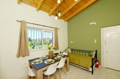 a dining room with a table and chairs and a bed at Jimmy's Pool House in Kremasti