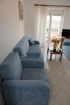 a living room with a blue couch and a table at Nephele Apartments in Faliraki