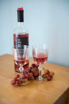 a bottle of wine and two glasses of grapes on a table at Nephele Apartments in Faliraki