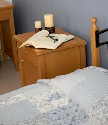 a desk with a book and candles and a bed at Nephele Apartments in Faliraki