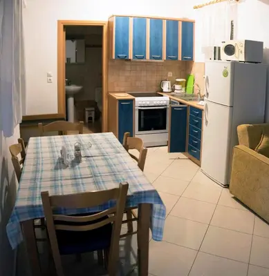 a kitchen with a table and a kitchen with blue cabinets at Nephele Apartments in Faliraki