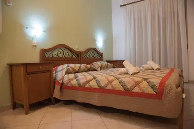 a bedroom with a bed with a nightstand and a bed sidx sidx sidx sidx at Nephele Apartments in Faliraki