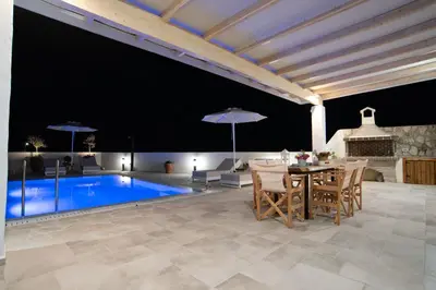 a patio with a table and chairs and a pool at Villa Despina in Afantou