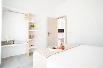a white bedroom with a bed and a mirror at Villa Despina in Afantou