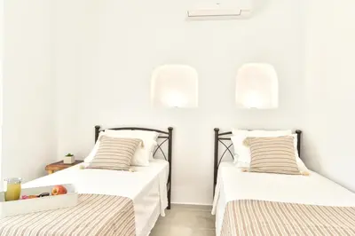 two beds in a room with white walls at Villa Despina in Afantou