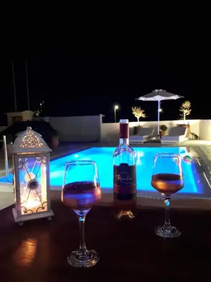 a bottle of wine and two wine glasses next to a swimming pool at Villa Despina in Afantou