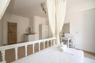 a white bedroom with a bed and a sink at Karpathios Studios Pefkos in Pefki Rhodes