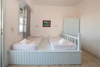 two beds in a room with white walls at Karpathios Studios Pefkos in Pefki Rhodes