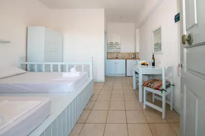 a bedroom with two beds and a sink and a table at Karpathios Studios Pefkos in Pefki Rhodes