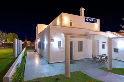 a white house with a sign on it at night at Villa Mare by Delfinia Resort in Kolimbia