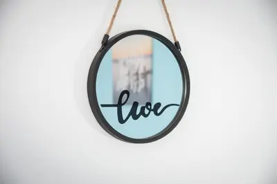 a round mirror hanging on a wall with the word live at Daisy's room in Archangelos