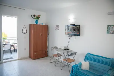 a living room with a blue couch and a table at Daisy's room in Archangelos