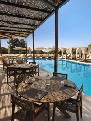 a patio with tables and chairs next to a swimming pool at Aethrion Villas & Suites in Gennadi