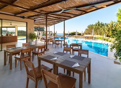 a restaurant with tables and chairs and a swimming pool at Aethrion Villas & Suites in Gennadi