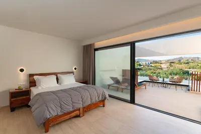 a bedroom with a bed and a balcony at Aethrion Villas & Suites in Gennadi