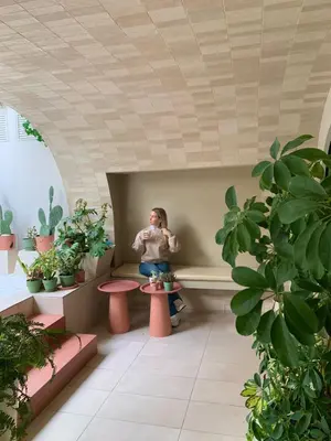 a woman sitting on a table in a room with plants at Central Grinn-in the heart of Rhodes,new&stylish! in Rhodes Town