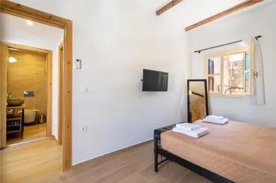 a bedroom with a bed and a television and a bathroom at Medieval Poem in Rhodes Town