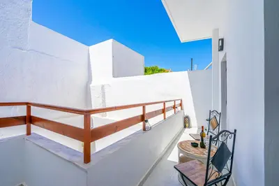 a balcony with stairs and a table on a white wall at Medieval Poem in Rhodes Town