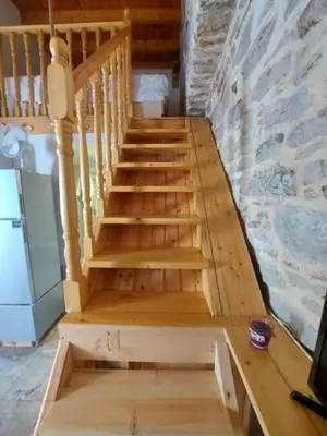 a wooden staircase in a room with a stone wall at Ήλιος Πατσακης in Symi