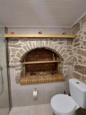 a bathroom with a stone fireplace with a toilet at Ήλιος Πατσακης in Symi