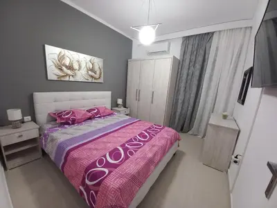 a bedroom with a large bed with pink sheets and pink pillows at Andreas Apartment in Rhodes Town