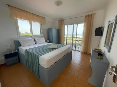a bedroom with a large bed and a balcony at Plastiras Sea View Apartments in Archangelos