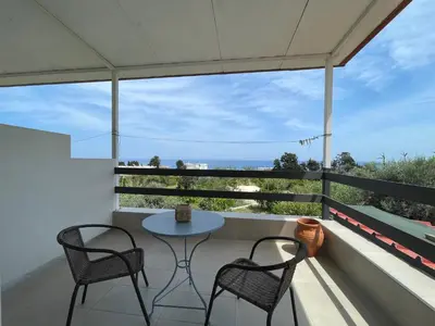 a patio with two chairs and a table on a balcony at Plastiras Sea View Apartments in Archangelos