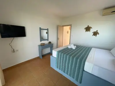 a bedroom with a bed and a flat screen tv at Plastiras Sea View Apartments in Archangelos