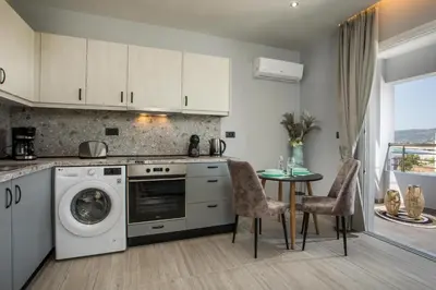 a kitchen with a washing machine and a table with chairs at Haraki Blue Dream Luxury Apartments in Haraki