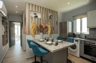 a kitchen with a table and blue chairs in it at Haraki Blue Dream Luxury Apartments in Haraki