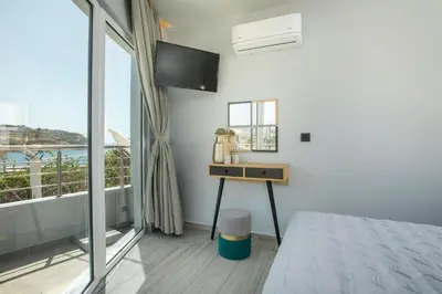 a bedroom with a bed and a desk and a window at Haraki Blue Dream Luxury Apartments in Haraki