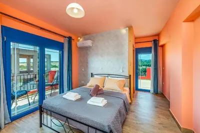 a bedroom with a bed with orange walls and a balcony at Olympia Villa in Gennadi
