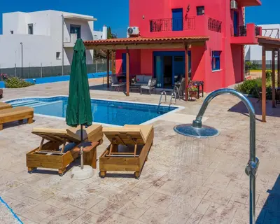 a swimming pool with two chairs and an umbrella at Olympia Villa in Gennadi