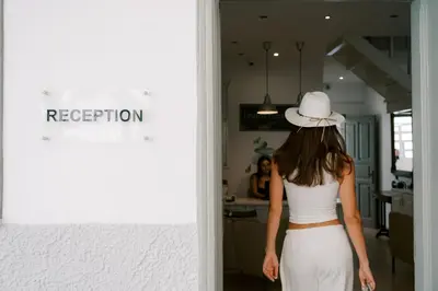 a woman wearing a white hat walking into a kitchen at Lindos Harmony Suites in Líndos