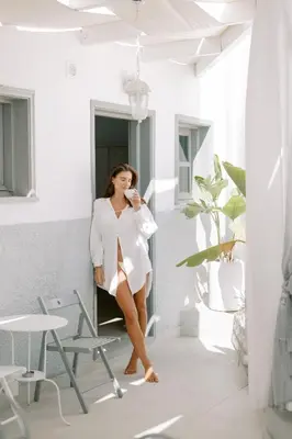 a woman in a white dress leaning against a wall at Lindos Harmony Suites in Líndos